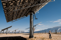 Person standing under a very large solar panel on solar farm