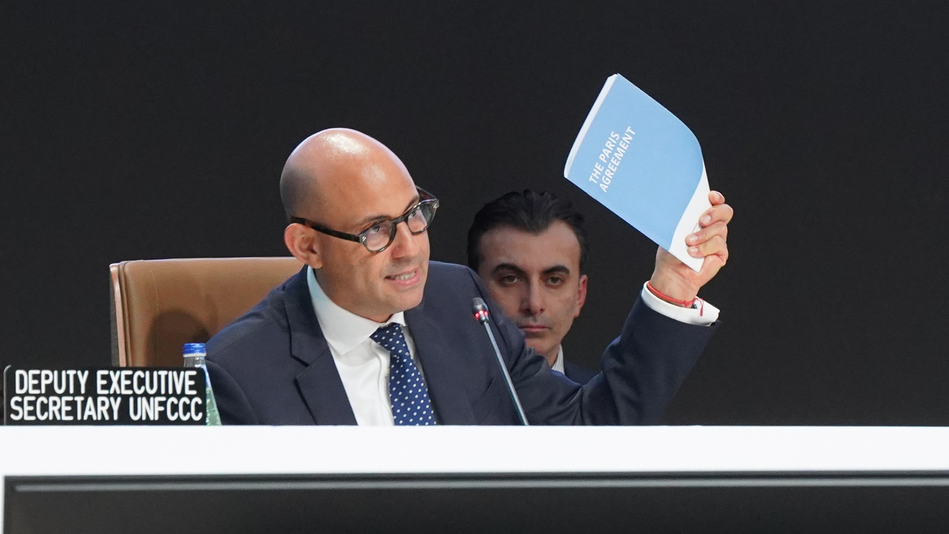 UN Climate Change Executive Secretary Simon Stiell holds up the Paris Agreement at the closing of COP29.