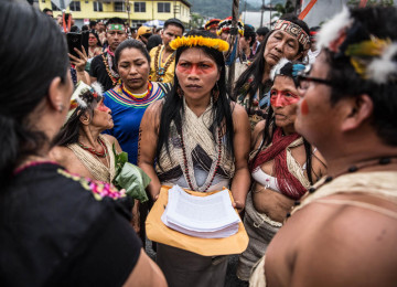 Picture of indigenous Nemonte Nenquimo holding a pile of documents in the middle of a crowd