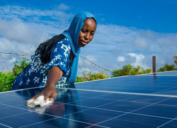 African woman cleaning solar panel