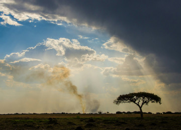 Rainclouds and fire over landscape in Zambia, Africa.