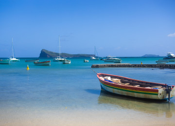 Colorful boats docked in pristine blue ocean with clear skies and distant islands in Mauritius