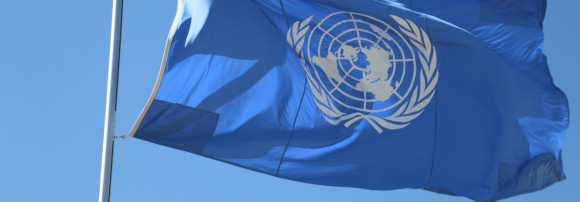 The UN flag flies in a blue sky.