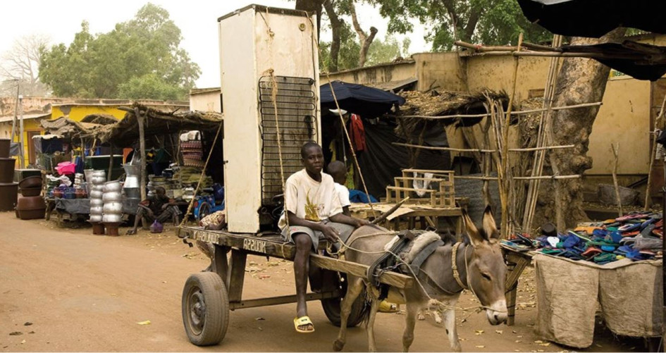 A donkey cart carries a refrigerator down a street