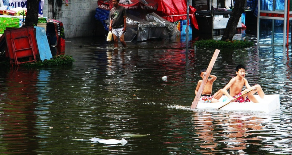 Boys paddle through flooded street