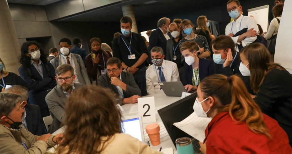 A group of delegates at the Bonn Climate Conference huddle together to discuss solutions.