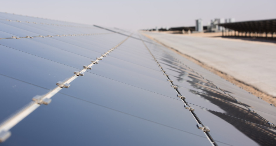 A row of solar panels gleams under a blue sky in a desert landscape, evoking feelings of hope.
