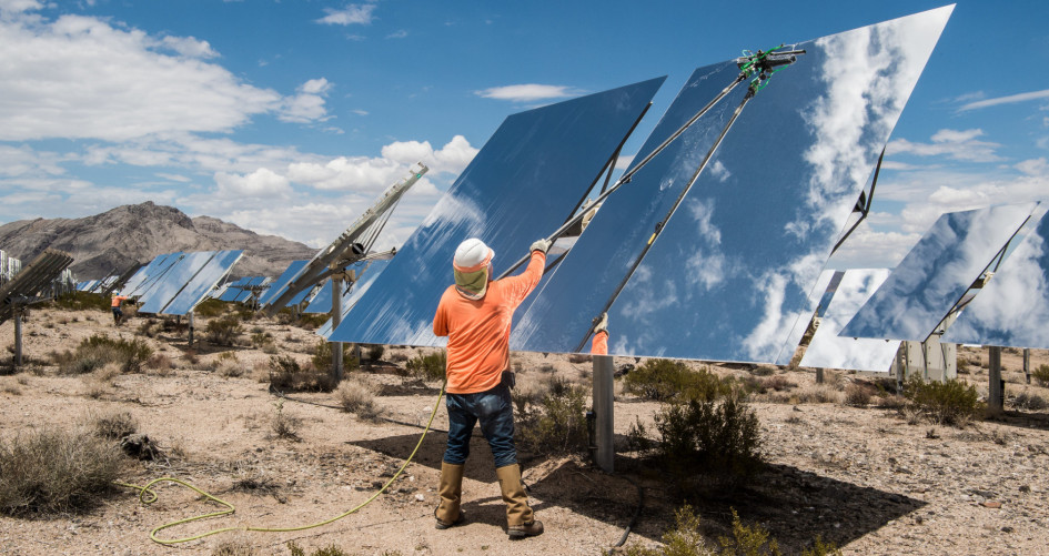 A person cleans a shining solar panel in the desert. 