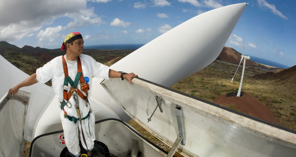 A worker stands up high inside a wind turbine overlooking a beautiful view.