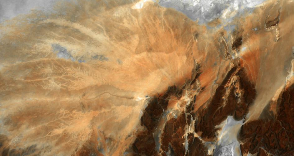 Barren ridges and fragmented mountains (lower right) border a vast expanse of arid plains etched with a complex system of dry streambeds.