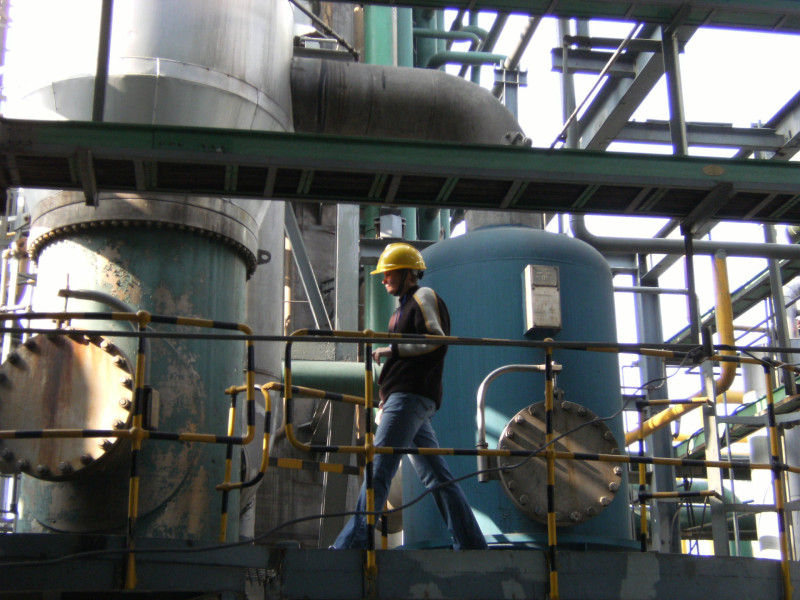 Man in hard hat walks through industrial plant for nitric acid production