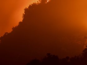 A wildfire rages at night in a mountainous town.