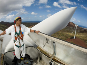 A worker stands up high inside a wind turbine overlooking a beautiful view.