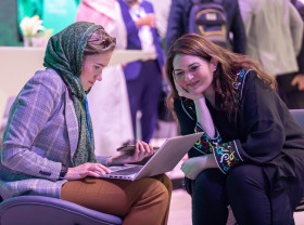 Two participants at MENA Climate Week 2023 consult information on a laptop.