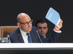 UN Climate Change Executive Secretary Simon Stiell holds up the Paris Agreement at the closing of COP29.