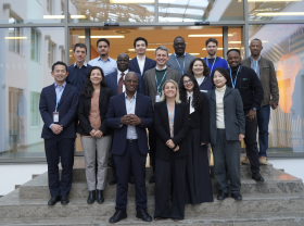 A group of negotiators from regions across the world standing on the stairs of a brightly lit building