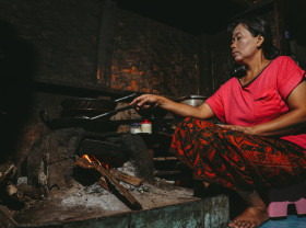 woman cooking with old woodfire cookstove which this project will replace