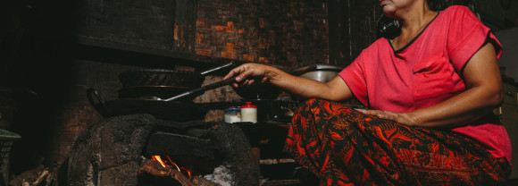 woman cooking with old woodfire cookstove which this project will replace
